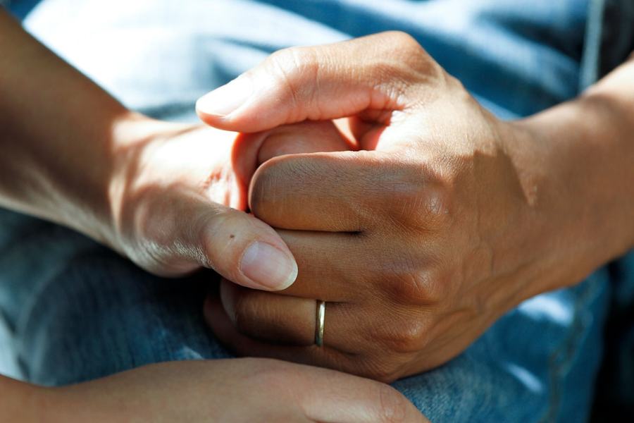 One person holding another's hands in a supportive gesture.