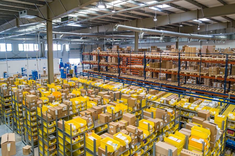 A large distribution warehouse with racked shelving and stacked cartons.